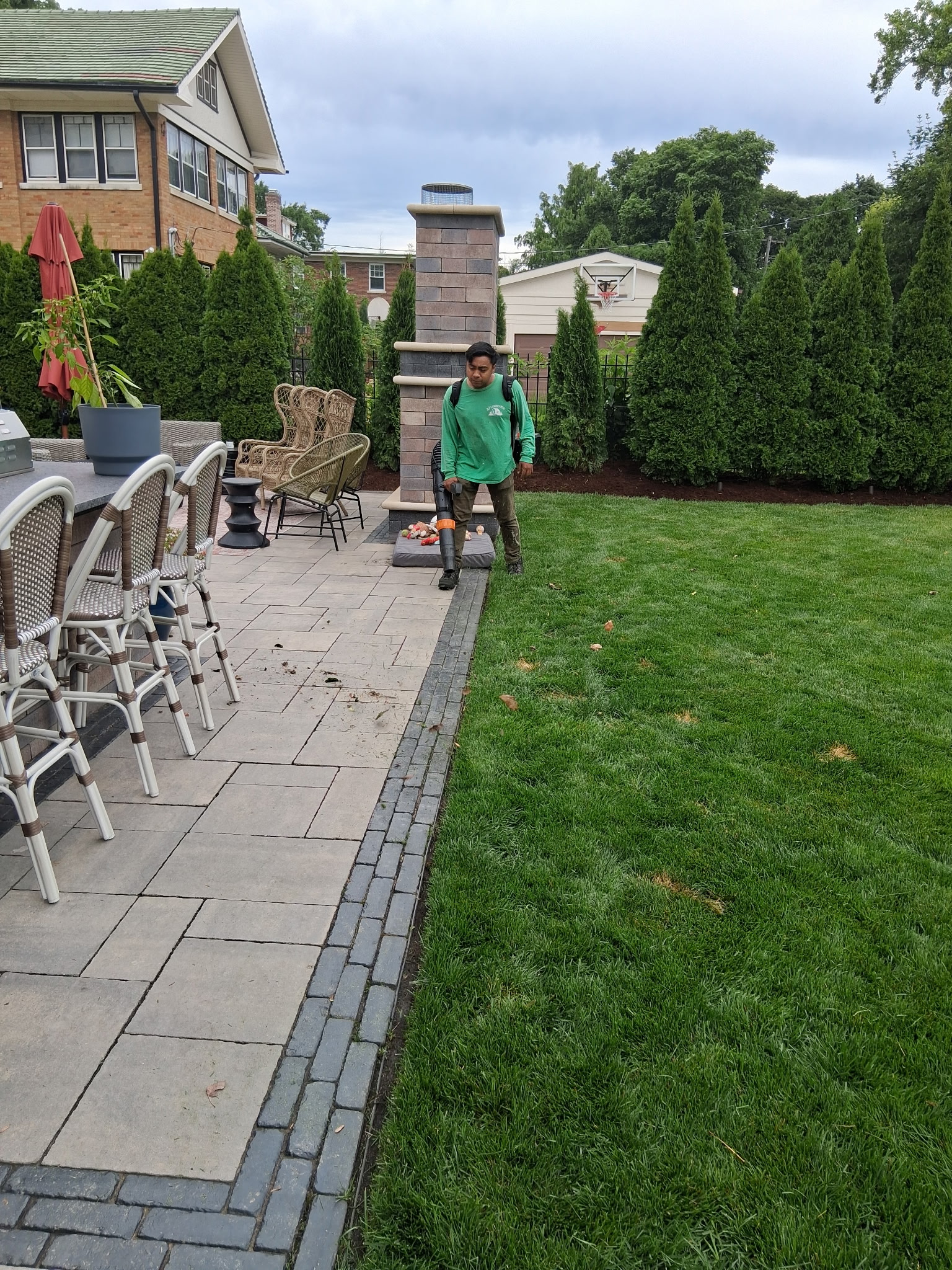 AJ Landscaping crew member blowing down a paver patio after a service visit
