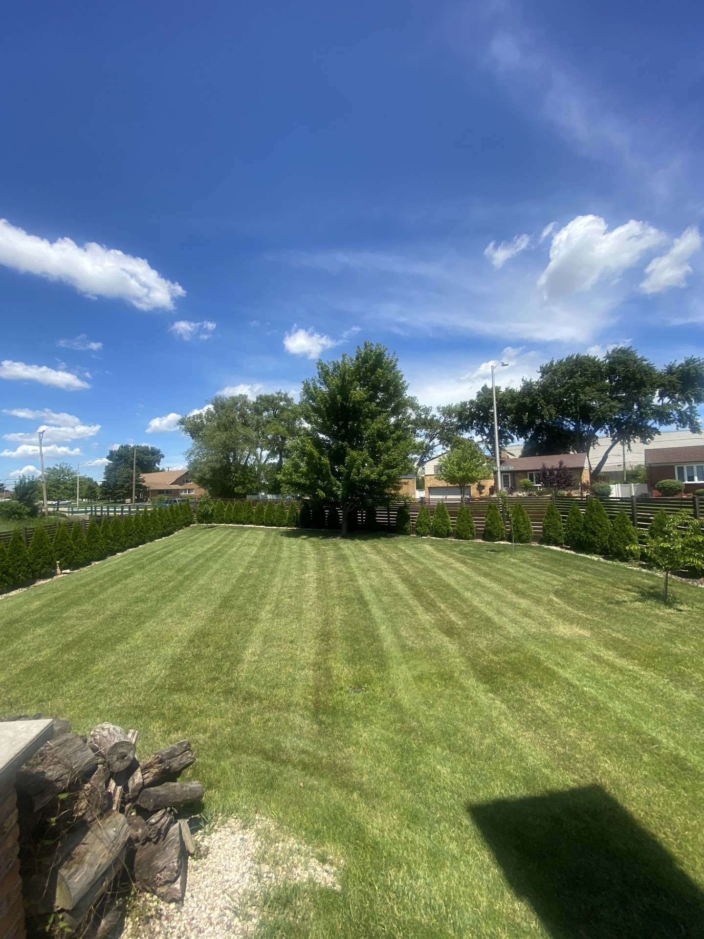 A large backyard lawn freshly mowed with clean mowing stripes by AJ Landscaping